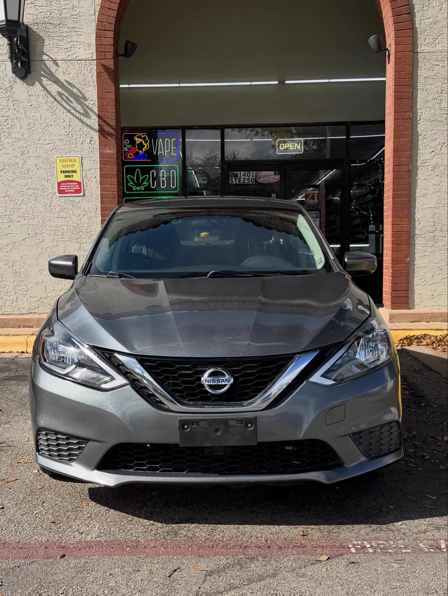 The grey Nissan Sentra photographed head-on in afternoon sun.