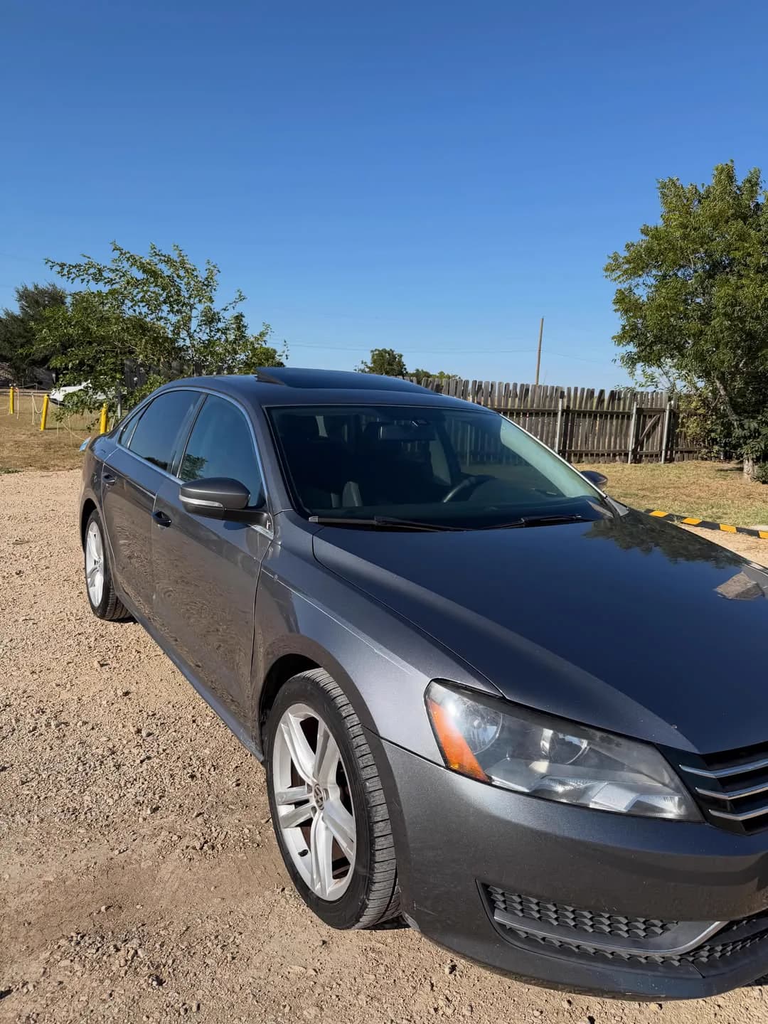 A grey Volkswagen Passat on the same lot, seen from the front three-quarter.